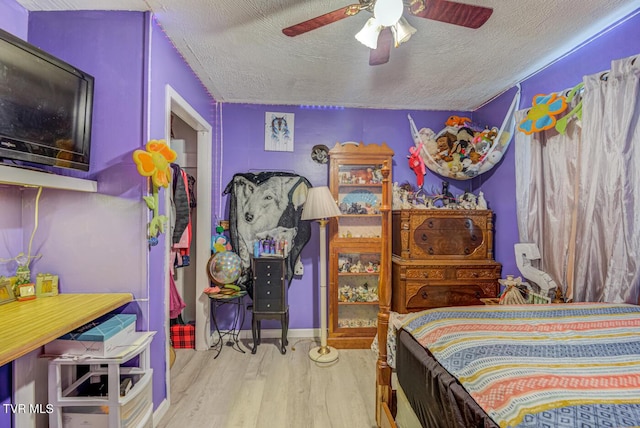 bedroom with a textured ceiling, wood finished floors, and a ceiling fan