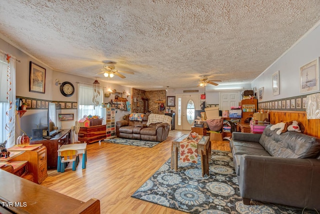 living area with wood finished floors, ceiling fan, ornamental molding, and a textured ceiling
