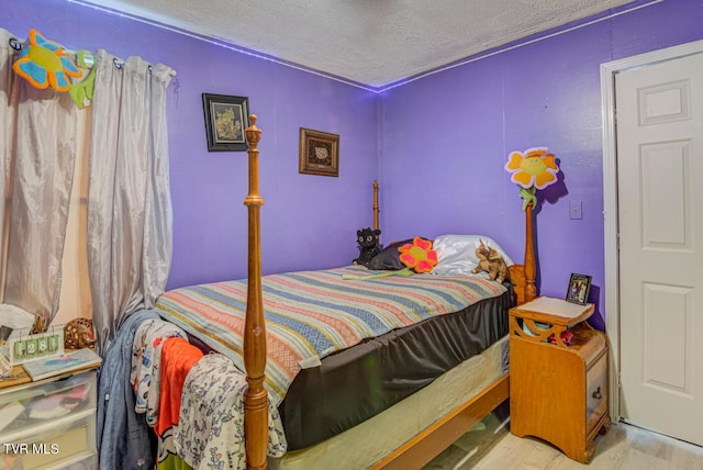 bedroom with a textured ceiling and wood finished floors