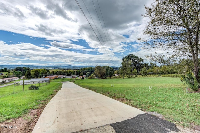 surrounding community with fence, a mountain view, and a yard