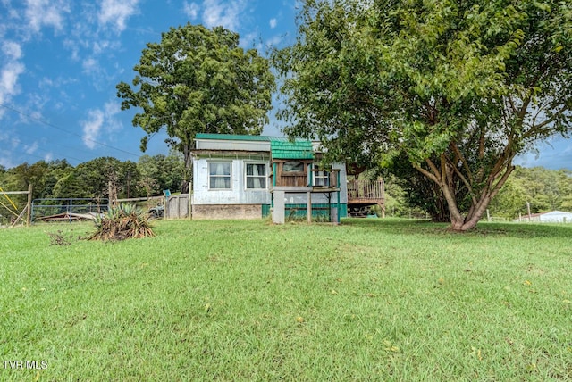 rear view of house with metal roof, fence, and a yard