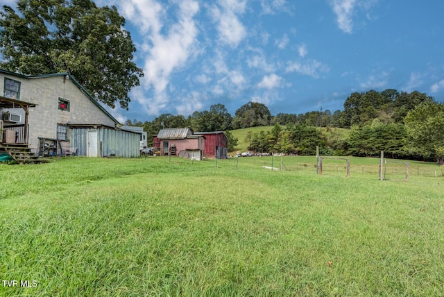 view of yard with an outbuilding, fence, and a rural view