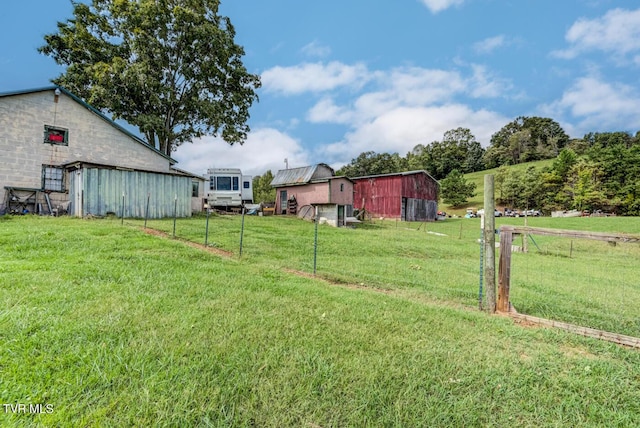 view of yard with an outbuilding, fence, and a pole building