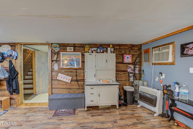 miscellaneous room featuring heating unit, wood finished floors, and stairway