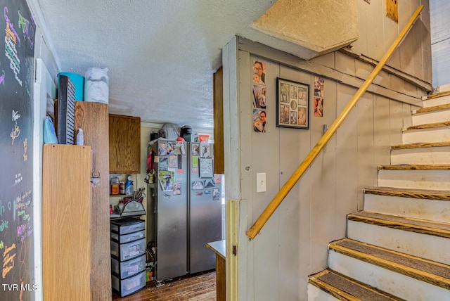 stairs featuring a textured ceiling and wood finished floors