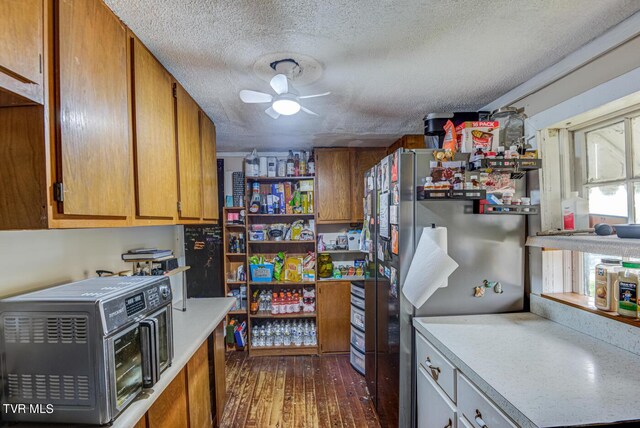 kitchen featuring ceiling fan, stainless steel refrigerator, dark hardwood / wood-style floors, and a textured ceiling