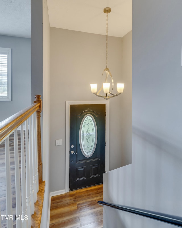 foyer entrance with hardwood / wood-style floors and a notable chandelier