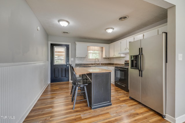 kitchen featuring light hardwood / wood-style floors, white cabinets, a kitchen island, black range with electric cooktop, and stainless steel fridge with ice dispenser