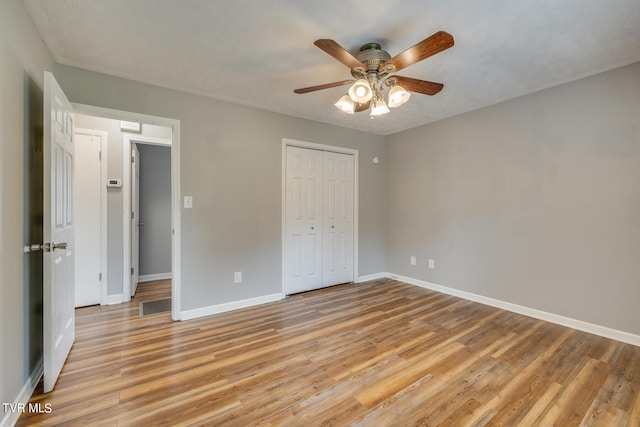 unfurnished bedroom featuring a closet, light hardwood / wood-style floors, ceiling fan, and a textured ceiling