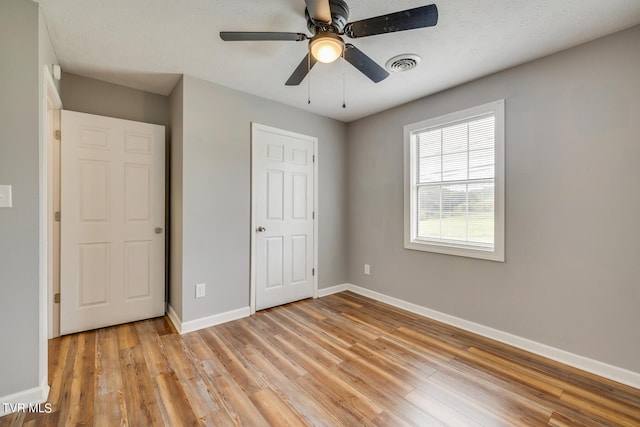 unfurnished bedroom featuring light hardwood / wood-style flooring, ceiling fan, and a textured ceiling