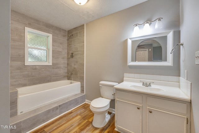 full bathroom with vanity, a textured ceiling, wood-type flooring, toilet, and tiled shower / bath