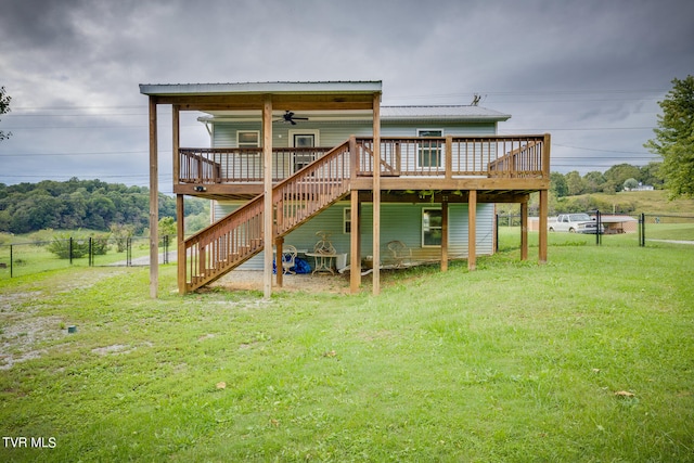 rear view of property with a yard, ceiling fan, and a wooden deck