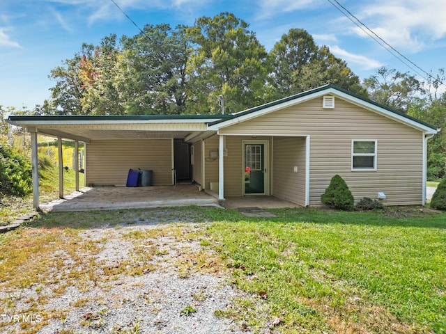 rear view of house featuring a carport, a lawn, and a patio area