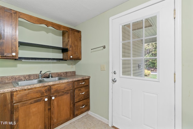 kitchen featuring a textured ceiling, sink, and light tile patterned floors