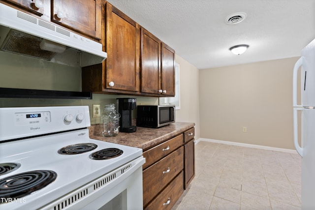 kitchen with a textured ceiling, white appliances, and light tile patterned floors