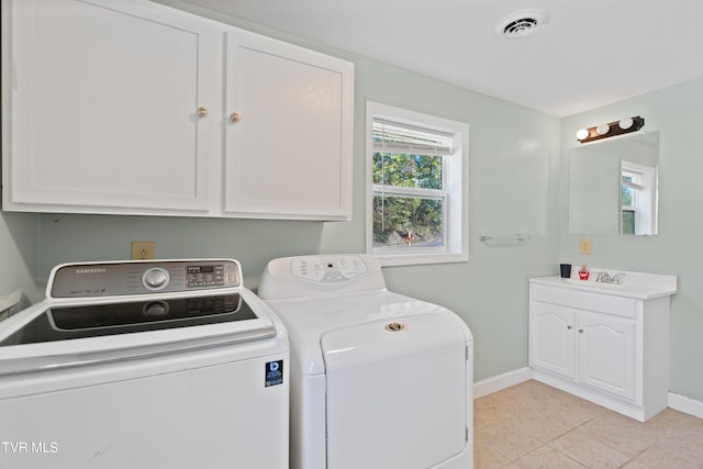 washroom with washer and dryer, light tile patterned flooring, cabinets, and sink