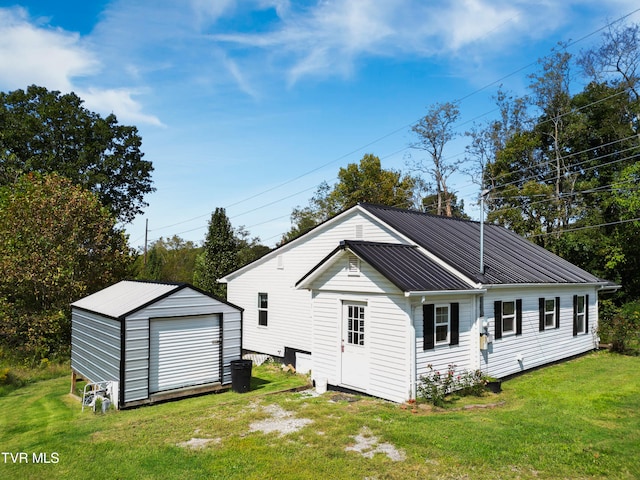 rear view of property featuring a storage unit, a garage, and a lawn