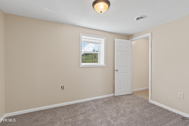 carpeted empty room featuring a textured ceiling