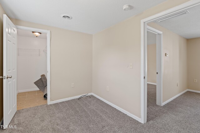 unfurnished bedroom with light colored carpet, a closet, and a walk in closet