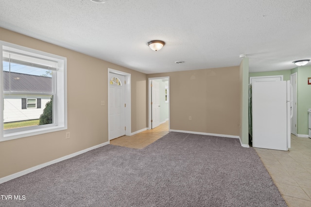 carpeted spare room with a textured ceiling