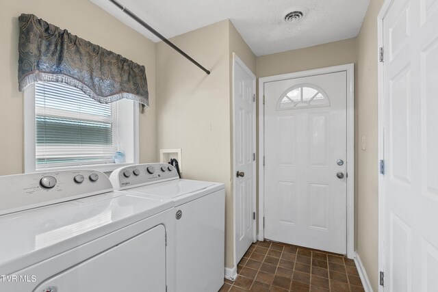 laundry area featuring a textured ceiling, a healthy amount of sunlight, and washing machine and clothes dryer