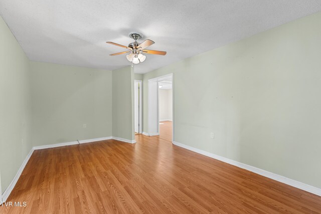 empty room featuring a textured ceiling, light wood-type flooring, and ceiling fan