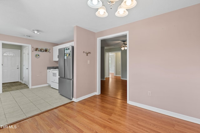 kitchen featuring light wood-type flooring, ceiling fan with notable chandelier, electric range, stainless steel fridge, and white cabinetry