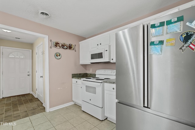 kitchen featuring white appliances, a textured ceiling, light tile patterned flooring, and white cabinets