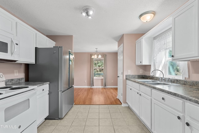 kitchen featuring white appliances, light tile patterned floors, an inviting chandelier, and white cabinets