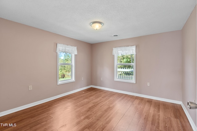 spare room featuring hardwood / wood-style flooring, a healthy amount of sunlight, and a textured ceiling