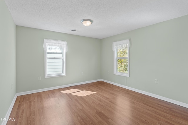 empty room with wood-type flooring and a textured ceiling