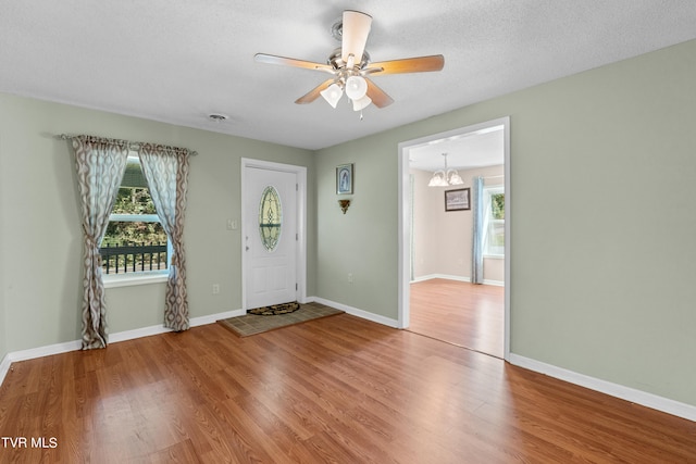 entrance foyer with a textured ceiling, hardwood / wood-style flooring, and ceiling fan with notable chandelier