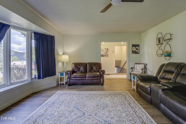 living area featuring plenty of natural light, a ceiling fan, wood finished floors, and a textured ceiling