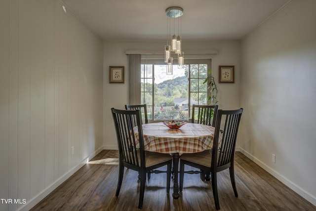 dining area featuring dark wood-type flooring, crown molding, baseboards, and a notable chandelier