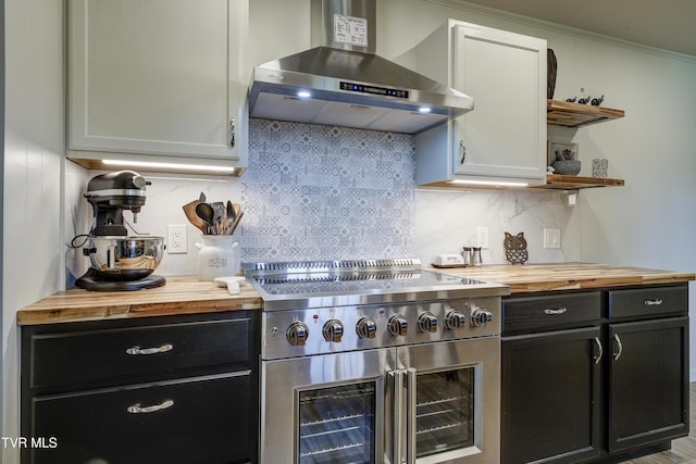 kitchen with wall chimney exhaust hood, tasteful backsplash, range with two ovens, open shelves, and butcher block counters