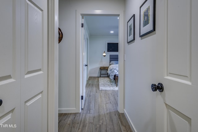 hallway with wood finished floors, baseboards, and ornamental molding