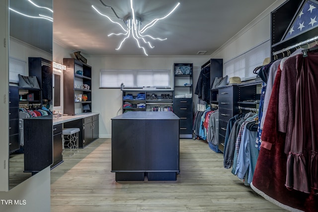 walk in closet featuring light hardwood / wood-style floors and an inviting chandelier