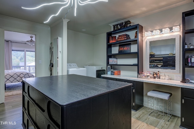 kitchen with independent washer and dryer, ornamental molding, a kitchen island, and light hardwood / wood-style flooring