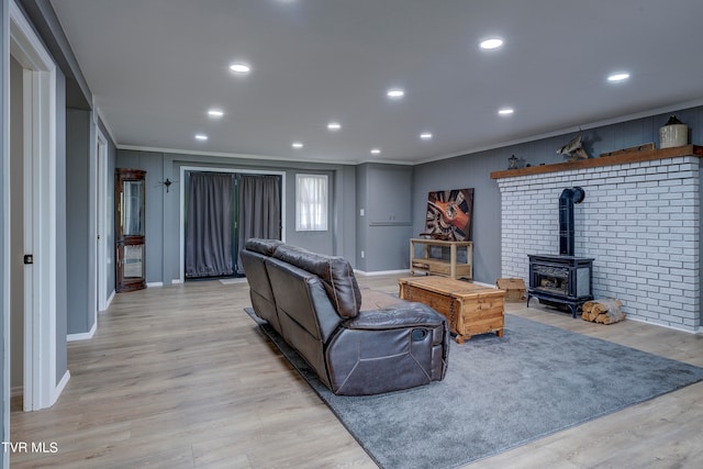 living room featuring ornamental molding, light hardwood / wood-style flooring, and a wood stove