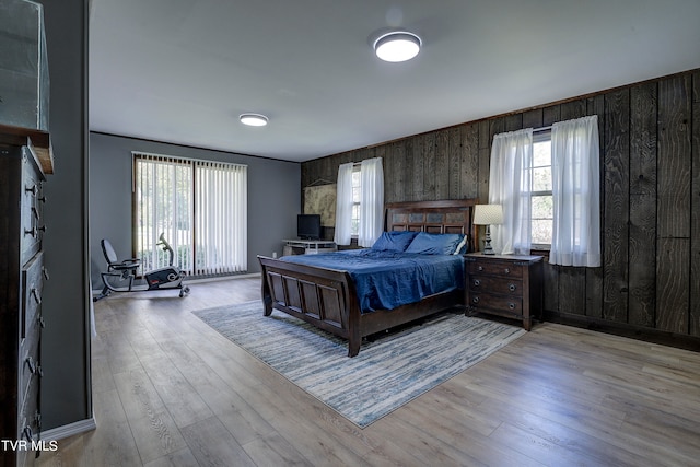 bedroom featuring wood walls and light hardwood / wood-style floors