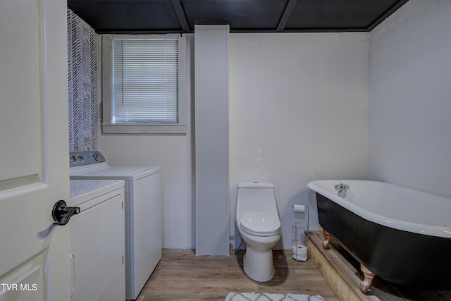 bathroom featuring a bathtub, hardwood / wood-style flooring, washing machine and clothes dryer, and toilet