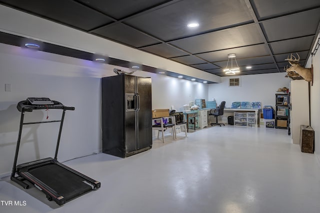 below grade area featuring black refrigerator with ice dispenser, visible vents, and recessed lighting