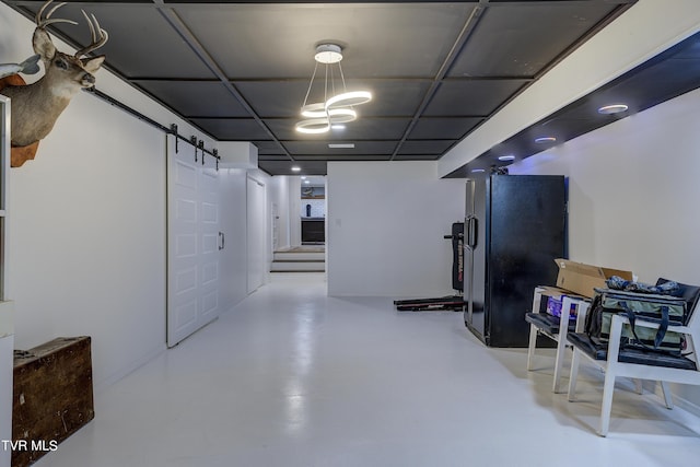 below grade area with a barn door and freestanding refrigerator