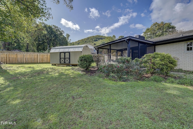 view of yard featuring an outdoor structure, fence, a shed, and a sunroom