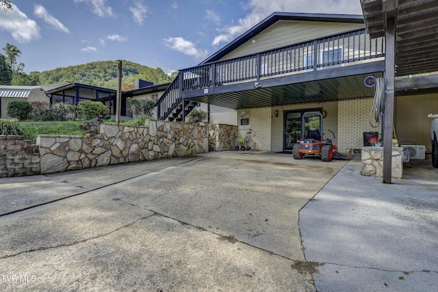 view of property exterior with concrete driveway, brick siding, and a deck