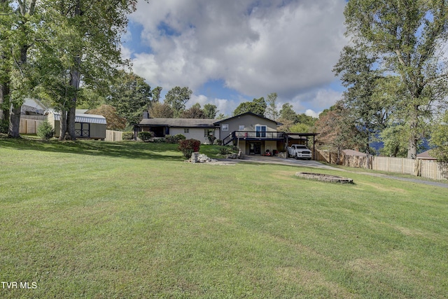 view of yard featuring a deck, an outdoor structure, fence, an attached carport, and stairs