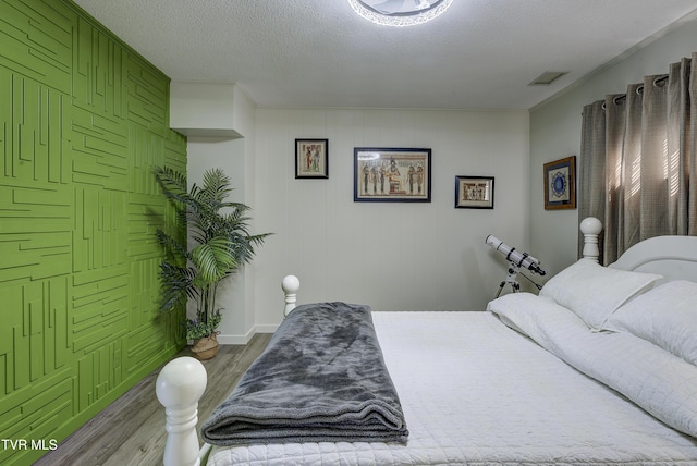 bedroom featuring a textured ceiling, wood finished floors, and visible vents