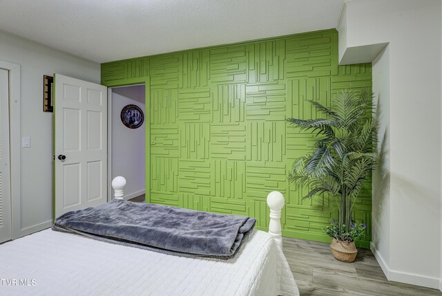 bedroom featuring baseboards, wood finished floors, and a textured ceiling