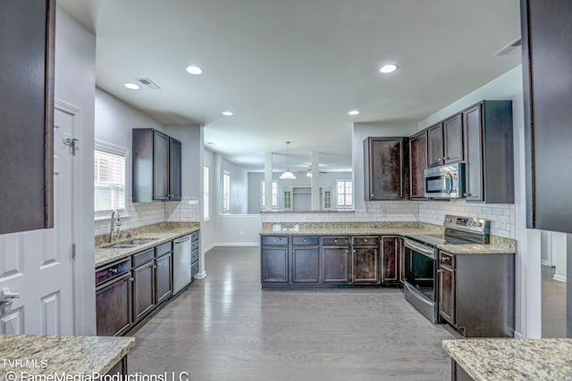 kitchen with pendant lighting, sink, tasteful backsplash, appliances with stainless steel finishes, and light wood-type flooring