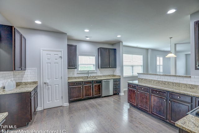 kitchen with hanging light fixtures, light hardwood / wood-style floors, tasteful backsplash, dishwasher, and sink